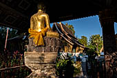 Wat Xieng Thong temple in Luang Prabang, Laos. The small pavilion with a seated Buddha statue. 